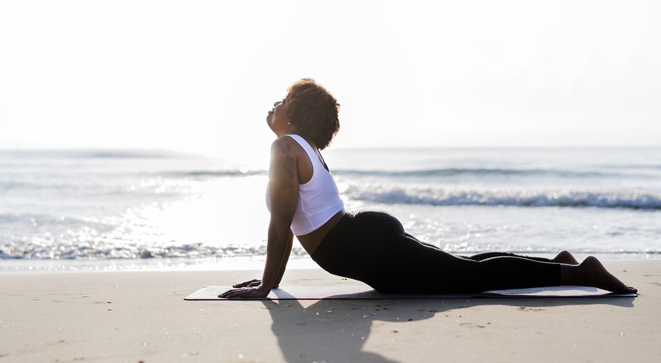 Femme noire qui fait du yoga sur la plage